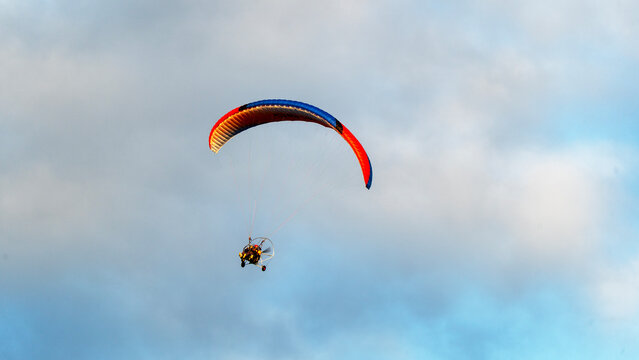 Paraglider soars above soft, cloudy sky