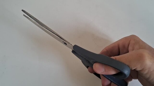 Hand holding sharp metal scissors and opening the blades in a smooth rhythmic motion sequence