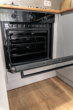 Modern built-in kitchen oven with open door and control knobs
