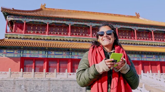 Smiling woman listening to an audioguide in the Forbidden City