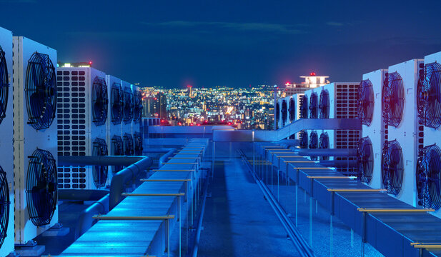 Rooftop HVAC system cools commercial buildings with air conditioning units, ventilation ducts, and city climate control at night