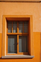 Obraz premium Portrait of yellow window on orange wall background 