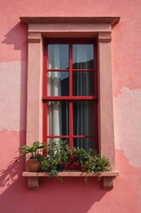 Fototapeta premium Portrait of red window on pink wall background 