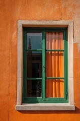 Obraz premium Portrait of green window on orange wall background 