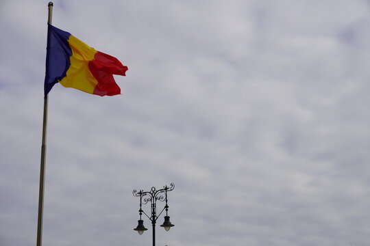 Romanian flag waiving above historic street lamp