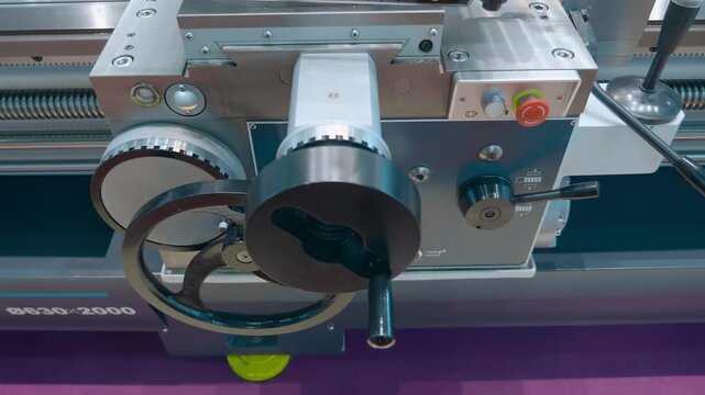 Lathe control levers and flywheels on the front panel for mechanical switching of equipment operating options. Closeup. Shot in motion
