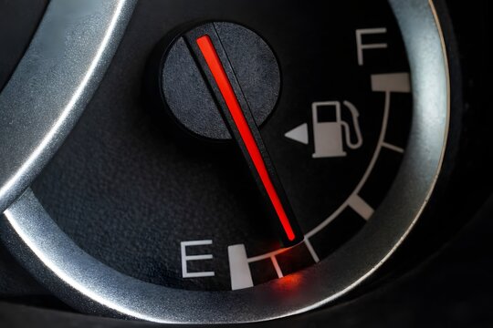 Low fuel gauge on car dashboard, close-up. 
