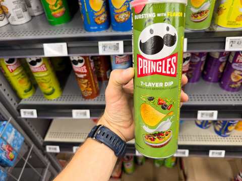 Pringles 7 Layer Dip Flavor Potato Crisps Can Held in Hand at Grocery Store Snack Aisle