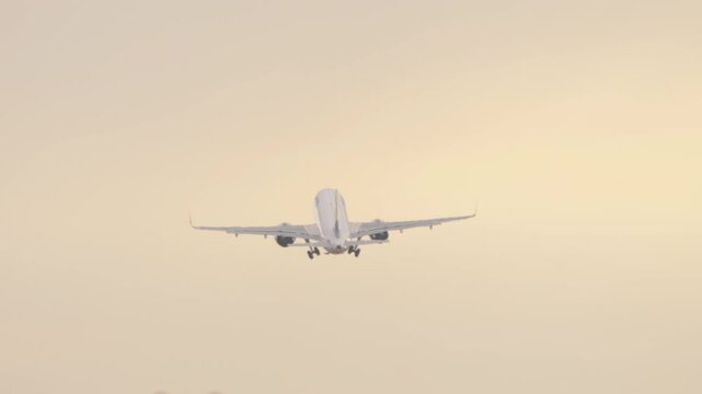 Jet aircraft taking off and climbing after departure from Almaty Airport during early morning sunrise light.