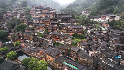 Obraz premium Foggy mountain village with layered wooden houses and riverside streets aerial view