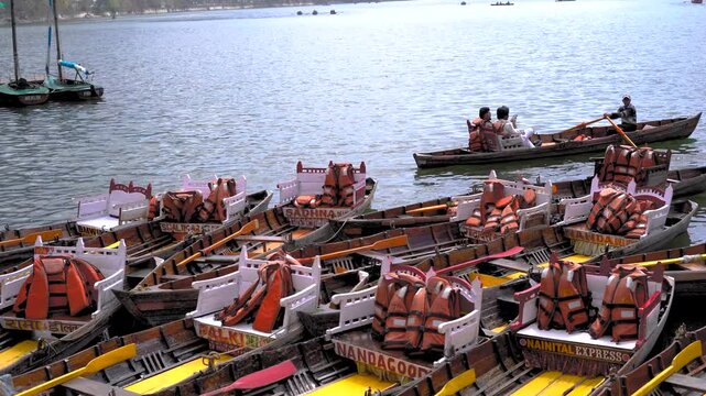 Rowing boats with orange life jackets waiting at the shore of Naini Lake in Nainital, India