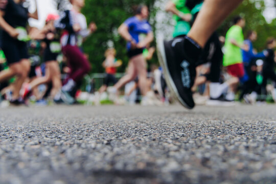 Marathon runners crowd, sportsmen participants start running the half-marathon in the city streets, crowd of sportswomen joggers in motion, group of athletes outdoor training competition in summer day