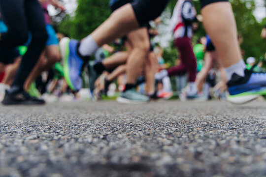Marathon runners crowd, sportsmen participants start running the half-marathon in the city streets, crowd of sportswomen joggers in motion, group of athletes outdoor training competition in summer day