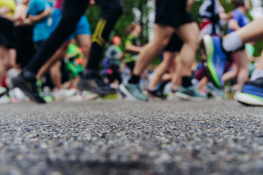 Marathon runners crowd, sportsmen participants start running the half-marathon in the city streets, crowd of sportswomen joggers in motion, group of athletes outdoor training competition in summer day