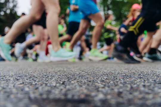 Marathon runners crowd, sportsmen participants start running the half-marathon in the city streets, crowd of sportswomen joggers in motion, group of athletes outdoor training competition in summer day