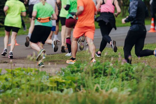 Marathon runners crowd, sportsmen participants start running the half-marathon in the city streets, crowd of sportswomen joggers in motion, group of athletes outdoor training competition in summer day