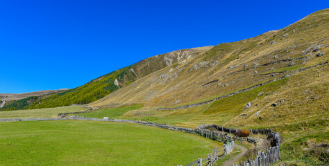 Blick über alpine Bergwiesen auf den kleinen Weiler Melag im herbstlichen Langtauferer Tal in Südtirol © Ilhan Balta