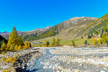 Blick über den steinigen Karlinbach auf den Weiler Melag im herbstlichen Langtauferer Tal, Südtirol © Ilhan Balta