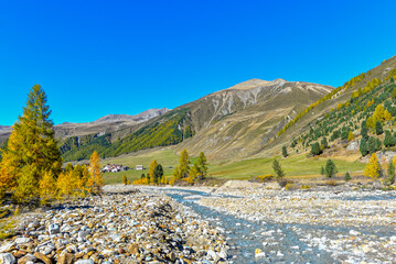 Blick über den steinigen Karlinbach auf den Weiler Melag im herbstlichen Langtauferer Tal, Südtirol © Ilhan Balta