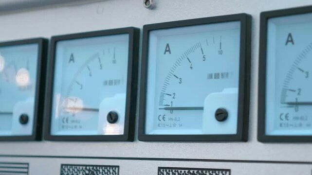 A long row of square pointer ammeters and a voltmeter on a industrial equipment. Closeup. Shot in motion