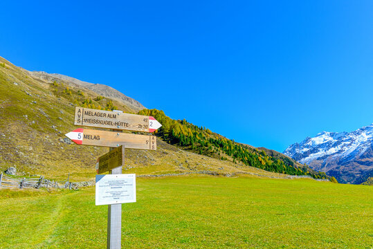 Wanderwegweiser im Langtauferer Tal mit Blick auf schneebedeckte Alpengipfel, S&uuml;dtirol