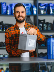 Auto parts store worker holding car battery