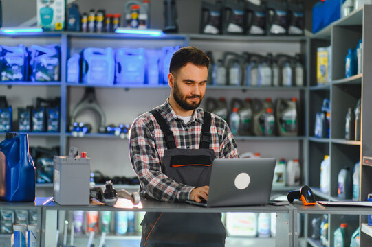 Mechanic worker managing auto parts inventory on laptop