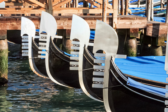 Traditional gondolas with iconic ferro prows moored in a canal in Venice, Italy.