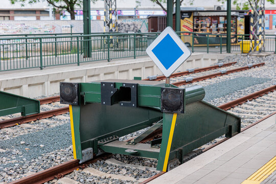 Green Railway Buffer Stop at Urban Train Platform With Blue Priority Sign and End-of-Line Tracks