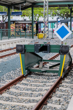 Green Railway Buffer Stop at Urban Train Platform With Blue Priority Sign and End-of-Line Tracks