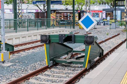 Green Railway Buffer Stop at Urban Train Platform With Blue Priority Sign and End-of-Line Tracks