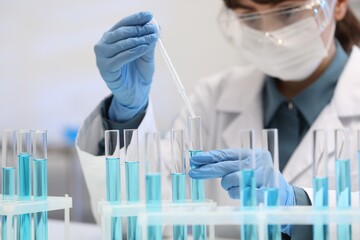 Fototapeta premium Scientist dripping blue liquid into test tube in laboratory, selective focus