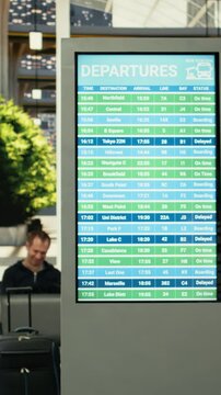 African american traveler checking timetable on departure board in bus terminal, waiting for long-haul interstate coach. Diverse commuters in transit hub for life in motion concept.