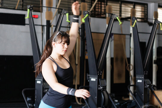 Young woman training on a ski erg machine at a gym, focusing on strength, fitness, and active lifestyle