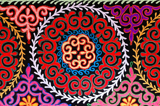 Close-up traditional Mongolian embroidery pattern with multiple rings of white, red, blue and yellow