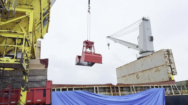 ship crane with grab take cargo of wheat in bulk from ship and bring to hopper on berth