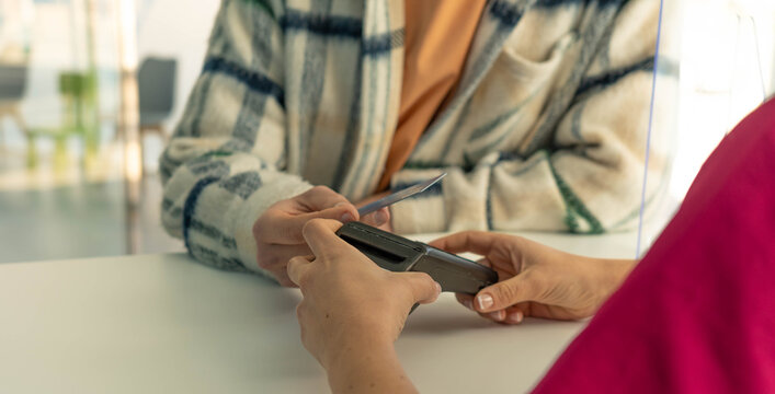 Customer making contactless payment with credit card at retail checkout