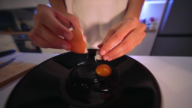Closeup of hands breaking egg into bowl in home setting