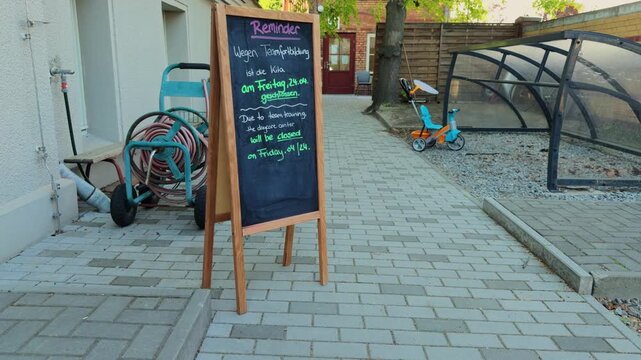Bilingual chalkboard reminder outside a public kindergarten in Berlin announcing closure for teacher training. Education, childcare administration, and international community concept.