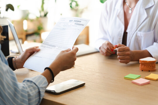 A patient reviews a medical document with a healthcare professional in a bright office setting.