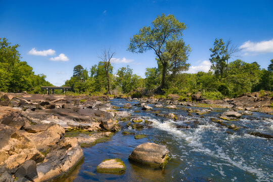 A beautiful landscape of the Haw River in the forest in Pittsboro. North Carolina in the United States with a bridge in the background under a blue sky.