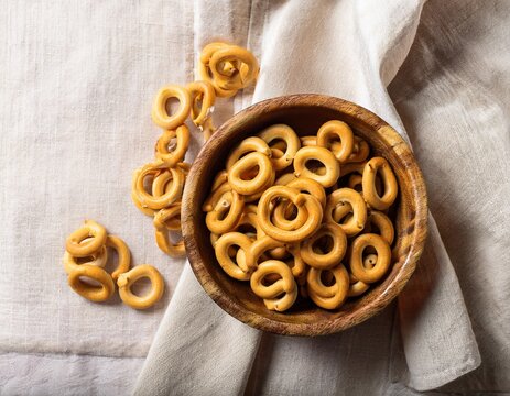 traditional italian snack taralli or tarallini in wooden bowl over light linen napkin background rustic shot of taralli appetizer with copy space top view or flat lay