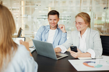 Obraz premium Team members engage in a dynamic brainstorming session with laptops and smartphones at a modern office in the afternoon