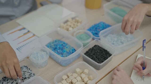 Hands sorting bead wood material in creative workshop design on table with container, recycling craft production and plastic granule sort for quality and sustainable manufacture