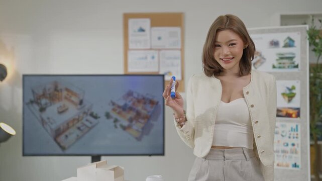 Smiling woman presenting office interior design model in room with display board and digital screen, model presentation in studio office meeting setting