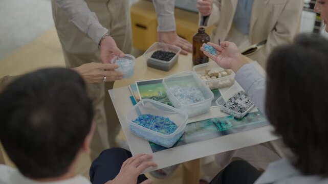 Teamwork meeting around table with sample container and glass bottle, hands selecting material creative workshop, recycling plastic sorting meeting with people around table, waste separation