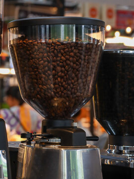Professional Coffee Grinder Hopper Filled with Roasted Coffee Beans in a Cafe. Vertical Image.