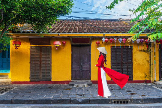Young Vietnam woman wearing Ao Dai culture traditional walking on local street at Hoi an, Vietnam