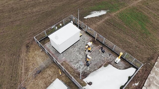 Aerial backward shot of a fenced gas pipeline station located in a field in Poland during winter season.