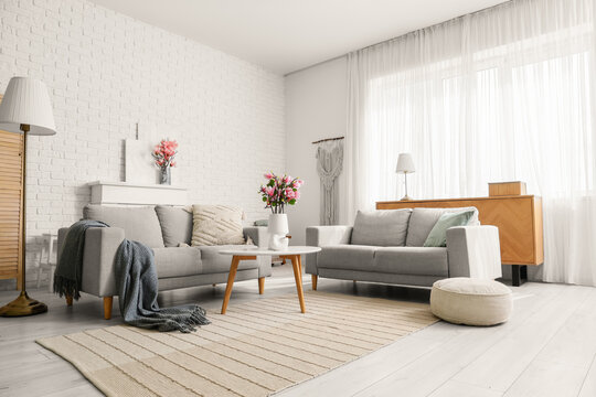 Interior of living room with sofas and artificial magnolia flowers in vases